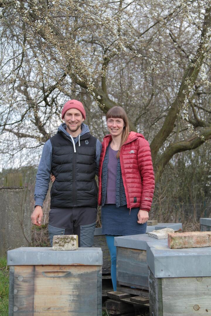 Mann und Frau vor Bienenstöcken